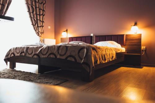 een slaapkamer met een groot bed met een houten hoofdeinde bij Pensiunea Willy Silvas in Tăşnad