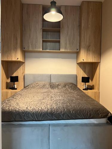 sypialnia z łóżkiem i drewnianymi szafkami w obiekcie Aquarius Kilińskiego 3 w mieście Grodzisk Mazowiecki