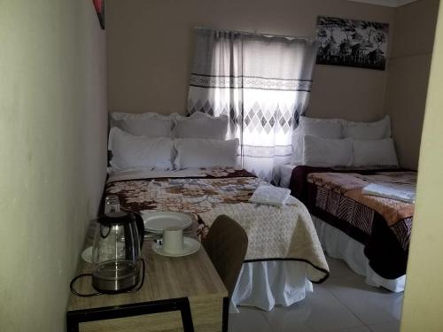 a small room with a bed and a table and a window at Pinto City Motel in Kempton Park
