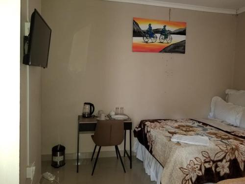 a bedroom with a bed and a desk with a computer at Pinto City Motel in Kempton Park