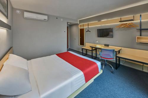 a hotel room with a bed and a desk and a chair at City Express by Marriott Monterrey Norte in Monterrey