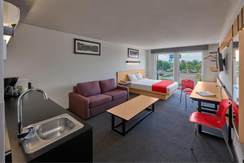 a room with a couch and a bed and a sink at City Express by Marriott Queretaro Jurica in Querétaro