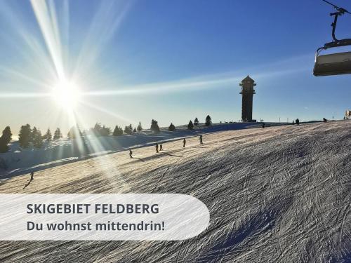 a snow covered slope with a ski lift and the sun at FeWo schwarzwaldschick Feldberg I wandern & biken ab Haustür I Whirlpool & Wlan & Balkon & Tiefgarage in Feldberg