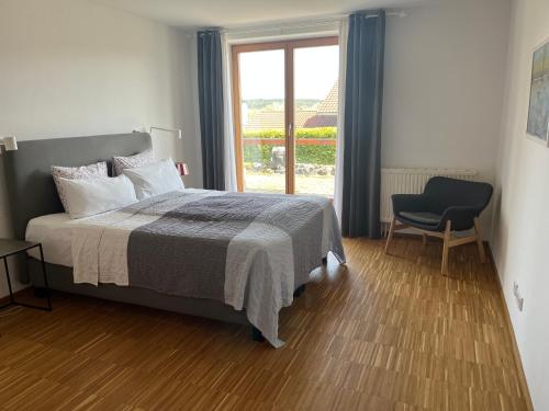 1 dormitorio con 1 cama, 1 silla y 1 ventana en Truchtling Appartements en Seeon-Seebruck