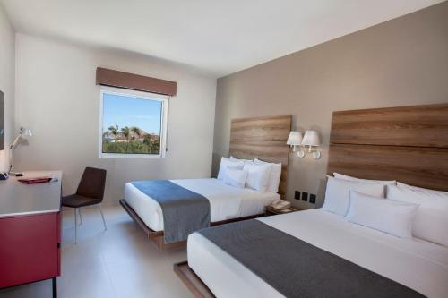 a hotel room with two beds and a desk at City Express Suites by Marriott Cabo San Lucas in Cabo San Lucas