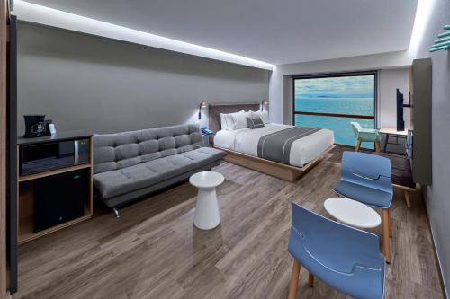 une chambre d'hôtel avec un lit et un canapé dans l'établissement City Express Plus by Marriott Ensenada, à Ensenada