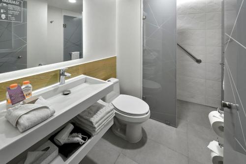 y baño con aseo, lavabo y ducha. en City Express Plus by Marriott Ensenada, en Ensenada