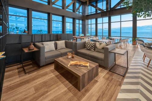 a living room with couches and tables and windows at City Express Plus by Marriott Ensenada in Ensenada