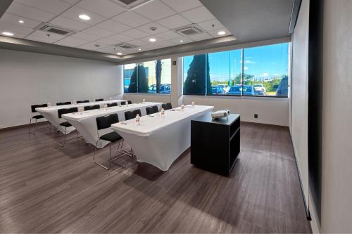 a conference room with white tables and chairs and a large window at City Express by Marriott San Luis Potosi Zona Industrial in San Luis Potosí
