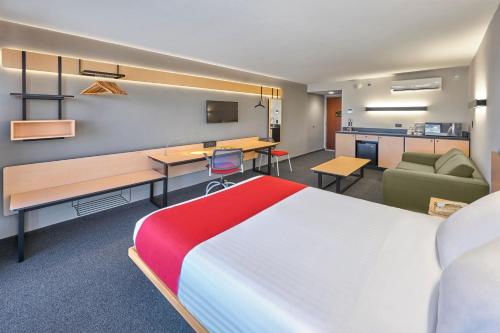 a hotel room with a large bed and a couch at City Express by Marriott Matamoros in Matamoros