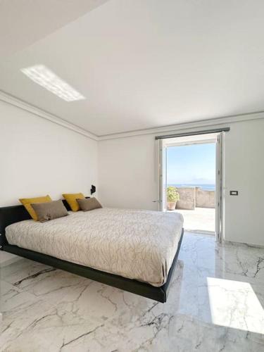 een witte slaapkamer met een groot bed en een groot raam bij Triton Capri in Capri