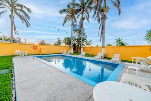 a swimming pool with tables and chairs and palm trees at City Express by Marriott Ciudad del Carmen in Ciudad del Carmen