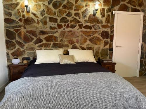 a bedroom with a large bed with a stone wall at Casa Rural La CaTaTa in Las Lagunas