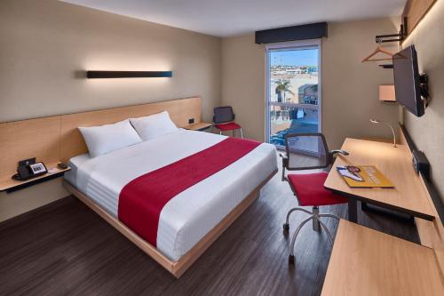 a hotel room with a bed and a desk and a window at City Express by Marriott Rosarito in Rosarito