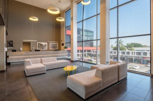a lobby with couches and a table and windows at City Express Plus by Marriott Guadalajara Palomar in Guadalajara