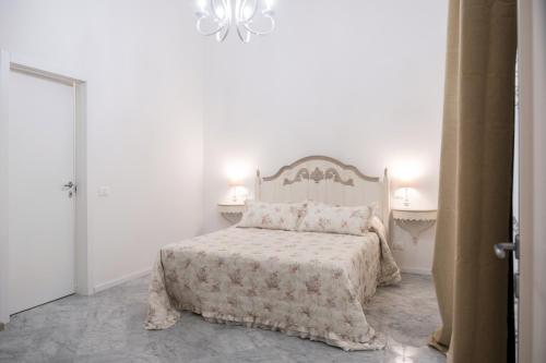 a white bedroom with a bed and a chandelier at Althea in Viareggio