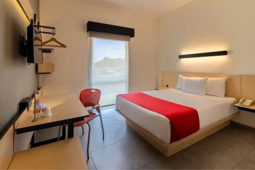 a hotel room with a bed and a desk and a window at City Express by Marriott Chetumal in Chetumal