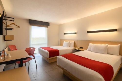 a hotel room with two beds and a desk at City Express by Marriott Chetumal in Chetumal
