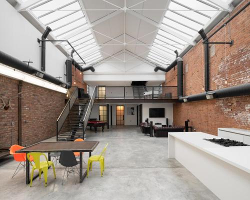 an industrial loft with a staircase and tables and chairs at Bedford Street Lofts in Leamington Spa