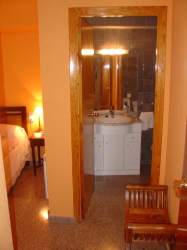 a bathroom with a sink and a mirror and a bedroom at Hostal Restaurante Arasa in Santa Bárbara