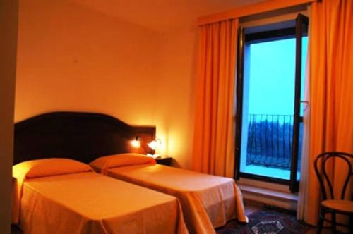 a hotel room with two beds and a window at Villa Butussi - L'ospitalità del Vino in Corno di Rosazzo