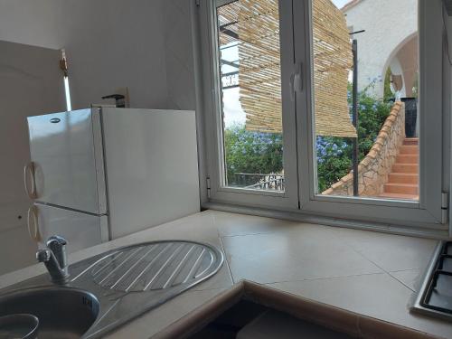 cocina con fregadero, nevera y ventana en Apartamentos CHRISTINA en Benicàssim