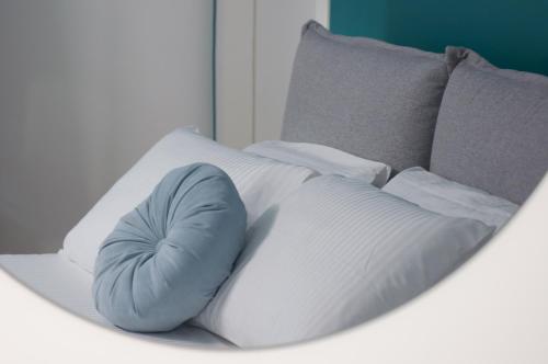 een wit bed met een blauw kussen erop bij VELVET HOME PESCARA - Luxury Apartment in Pescara