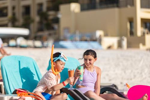 two young children sitting in chairs on the beach at The Royal Sands Resort & Spa in Cancún
