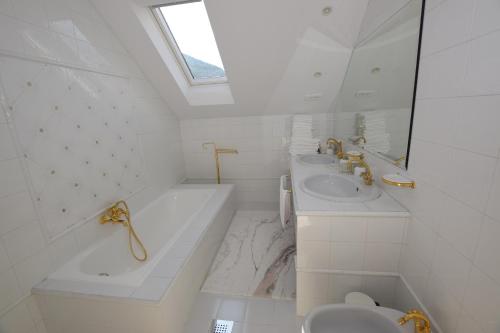 La salle de bains blanche est pourvue d'un lavabo, d'une baignoire et de toilettes. dans l'établissement EROS APARTMENT Kranjska Gora, à Kranjska Gora