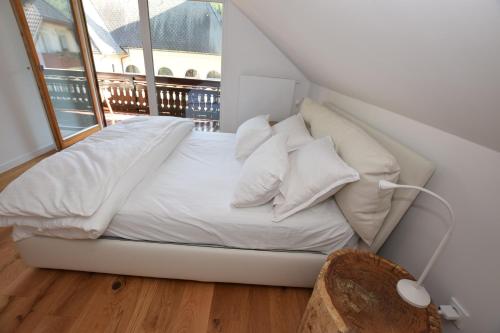 Cette chambre dispose d'une fenêtre et d'un lit avec des draps et des oreillers blancs. dans l'établissement EROS APARTMENT Kranjska Gora, à Kranjska Gora