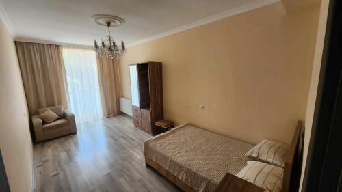 Un dormitorio con una cama y una silla y un televisor. en Apartment LL, en Kutaisi