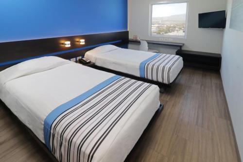 two beds in a room with a blue wall at City Express Junior by Marriott San Luis Potosi Zona Industrial in San Luis Potosí