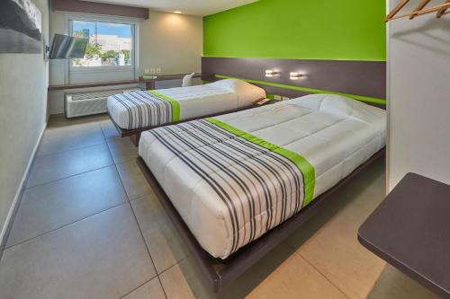 two beds in a room with a green wall at City Express Junior by Marriott Cancun in Cancún