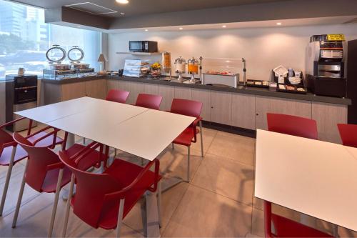 eine Küche mit roten Stühlen, einem Tisch und einer Theke in der Unterkunft City Express Junior by Marriott Cancun in Cancún