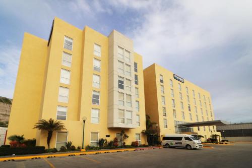 a yellow building with a white van parked in a parking lot at City Express by Marriott Tijuana Insurgentes in Tijuana