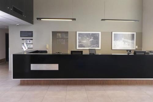 a lobby with a black counter with two pictures on the wall at City Express by Marriott Tijuana Insurgentes in Tijuana