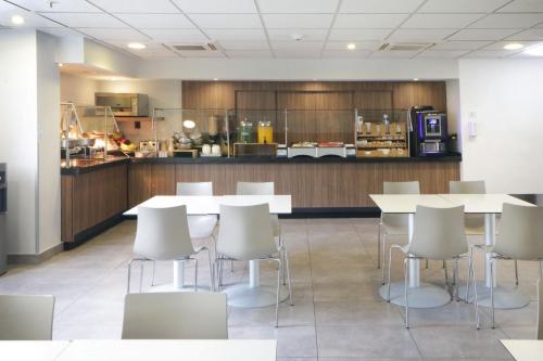 a cafeteria with white tables and chairs and a kitchen at City Express by Marriott Tijuana Insurgentes in Tijuana