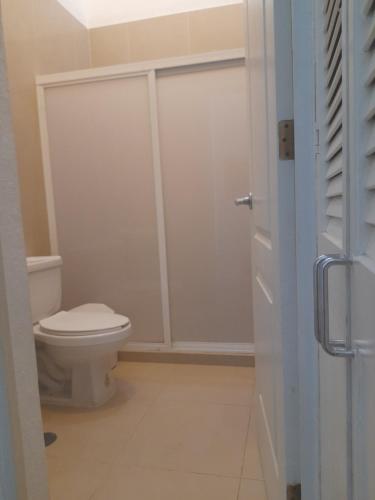 a bathroom with a toilet and a glass shower door at airbnb Acapulco Diamante in Acapulco