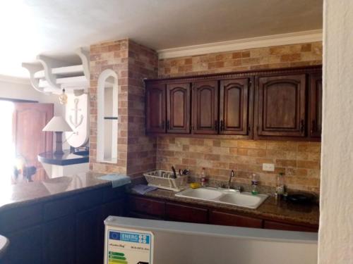 a kitchen with wooden cabinets and a sink at ARCOIRIS SHARE APARTMENT BAVARO PUNTA CANA in Punta Cana