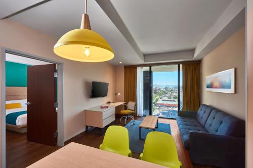 a hotel room with a couch and a bedroom at City Express Suites by Marriott Tijuana Rio in Tijuana
