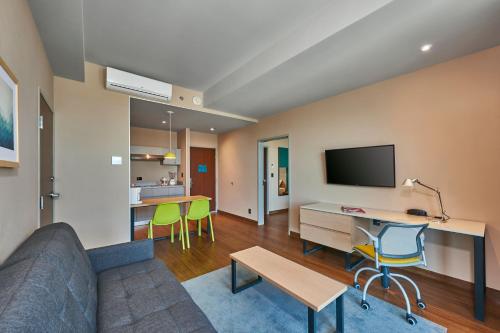 a living room with a couch and a desk and a tv at City Express Suites by Marriott Tijuana Rio in Tijuana