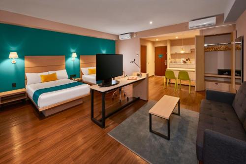 Habitación de hotel con cama y sala de estar. en City Express Suites by Marriott Tijuana Rio en Tijuana
