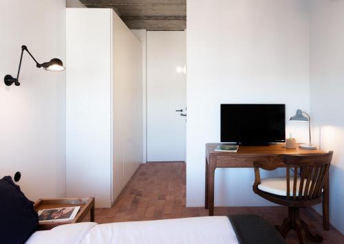 Schlafzimmer mit einem Schreibtisch, einem TV und einem Bett in der Unterkunft Columbano Suites Hotel Lisboa - Praça de Espanha, Sete Rios - Bookable parking in Lissabon