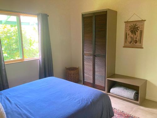a bedroom with a blue bed and a window at Seaside House and Aloha Bungalow in Pahoa