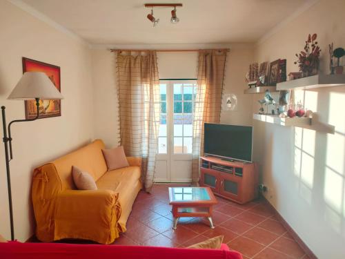 - un salon avec un canapé et une télévision dans l'établissement A casa do Almograve, à Almograve