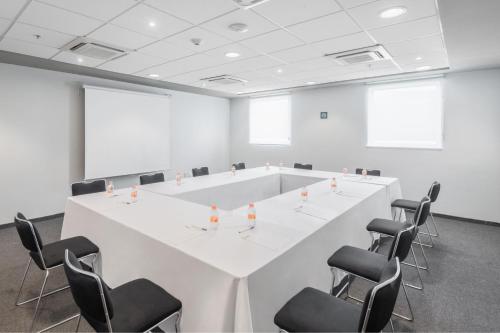 a conference room with a white table and chairs at City Express Junior by Marriott Villahermosa in Villahermosa