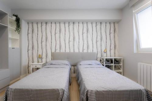 two beds in a small room with a window at Apartamento tranquilo y céntrico en Santander in Santander