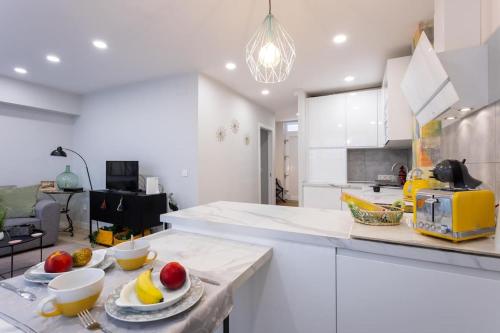a kitchen with white cabinets and bowls of fruit on a counter at Apartamento tranquilo y céntrico en Santander in Santander