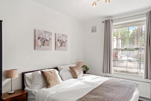 um quarto branco com uma cama e uma janela em Cosy in Catford two bed near station em Beckenham