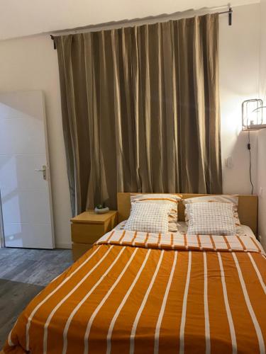 - une chambre dotée d'un lit avec une couverture rayée orange et blanche dans l'établissement Villa élégante et chaleureuse proche de Paris, à La Frette-sur-Seine
